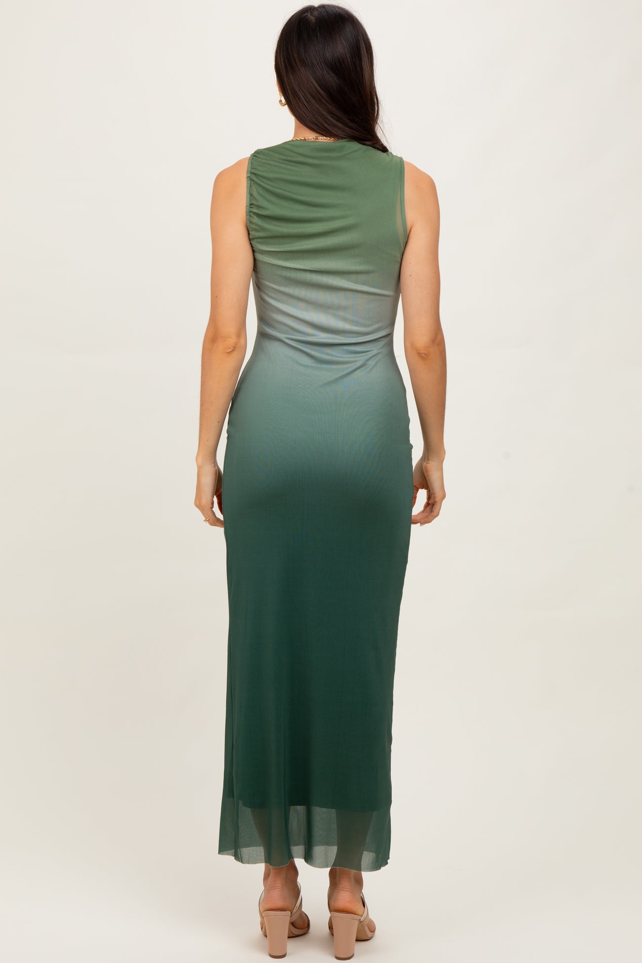 woman wearing a sleeveless green ombre maxi dress, showing the back view and side slit detail