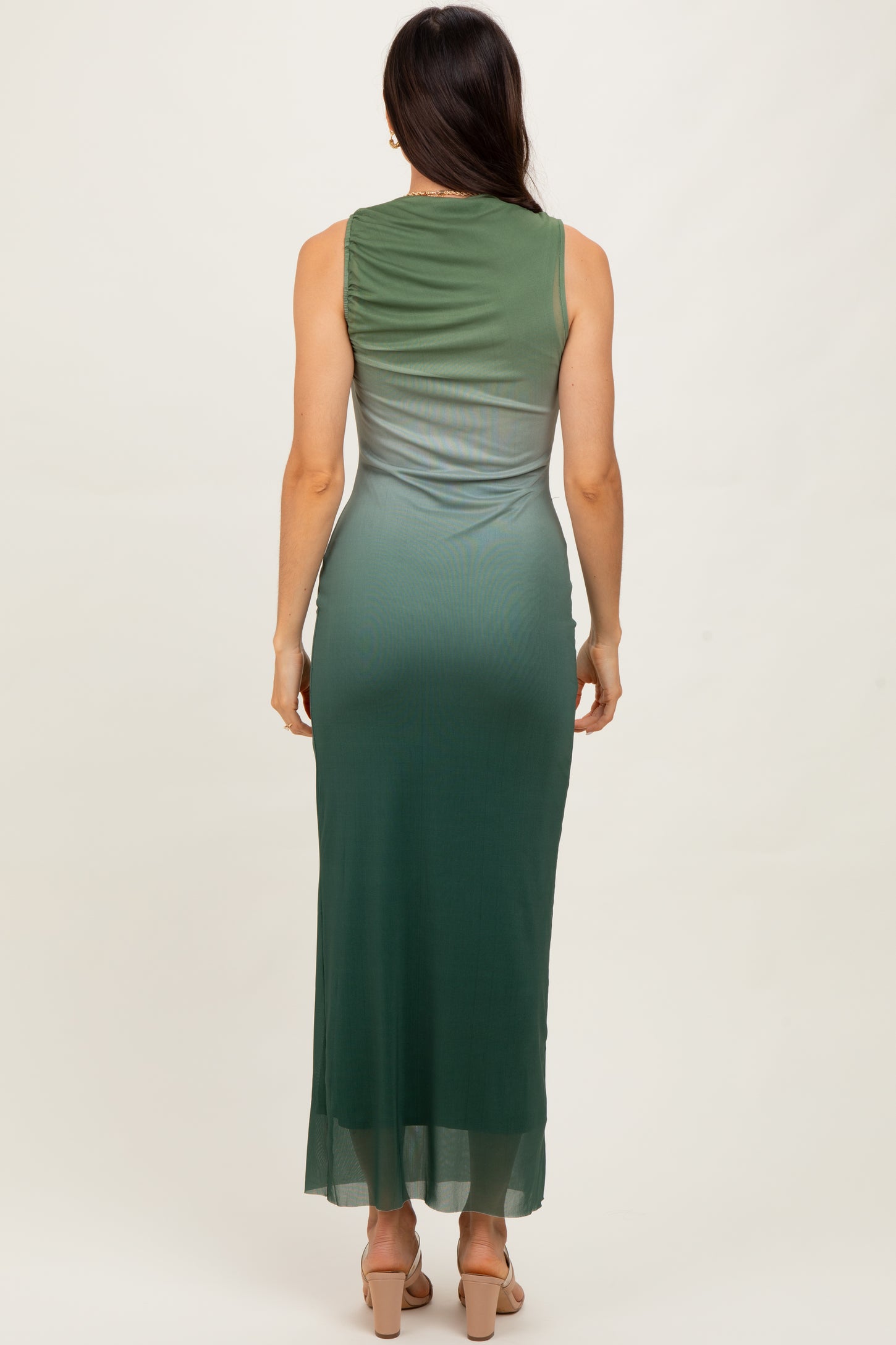 woman wearing a sleeveless green ombre maxi dress, showing the back view and side slit detail