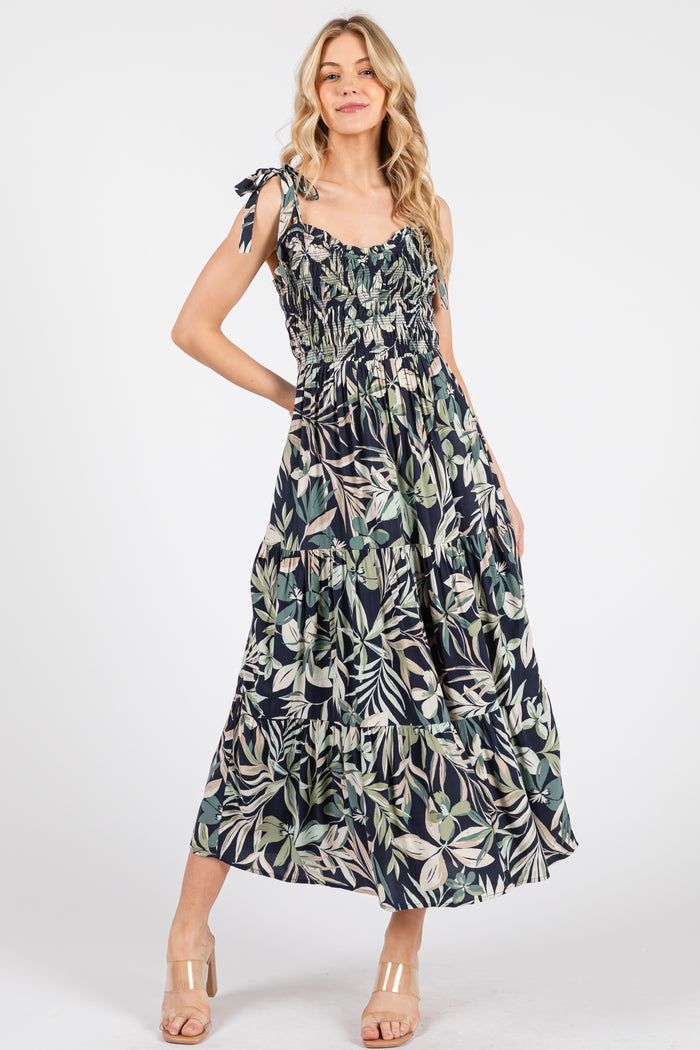 woman wearing a floral print maxi dress with tie straps and smocked bodice, standing against a white background