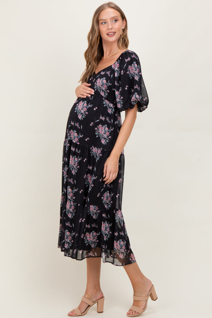 woman wearing a floral black maternity dress with short puff sleeves and a baby bump visible