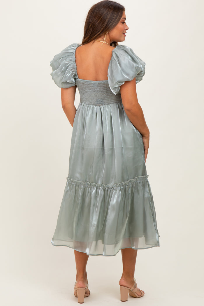 woman wearing a backless silver green maternity dress with puff sleeves and a tiered skirt