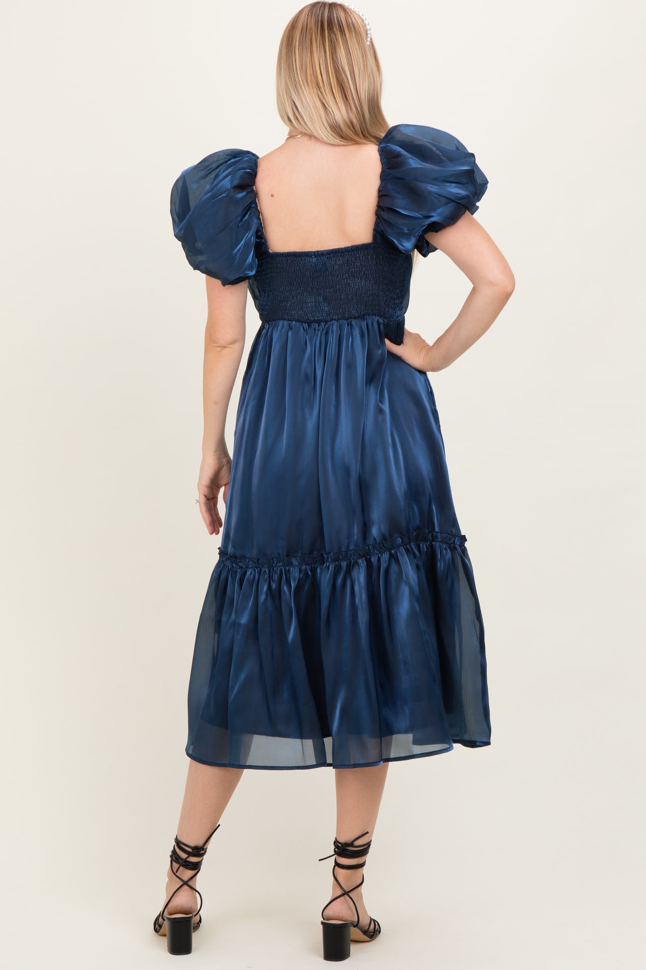 woman wearing a back view of a navy blue puff sleeve maxi dress with a smocked bodice and tiered skirt