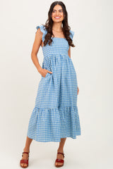 woman wearing a blue and white gingham checked maxi dress with ruffle sleeves and pockets