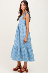 woman wearing a blue gingham ruffled maxi dress with a tiered skirt and brown chunky heeled sandals