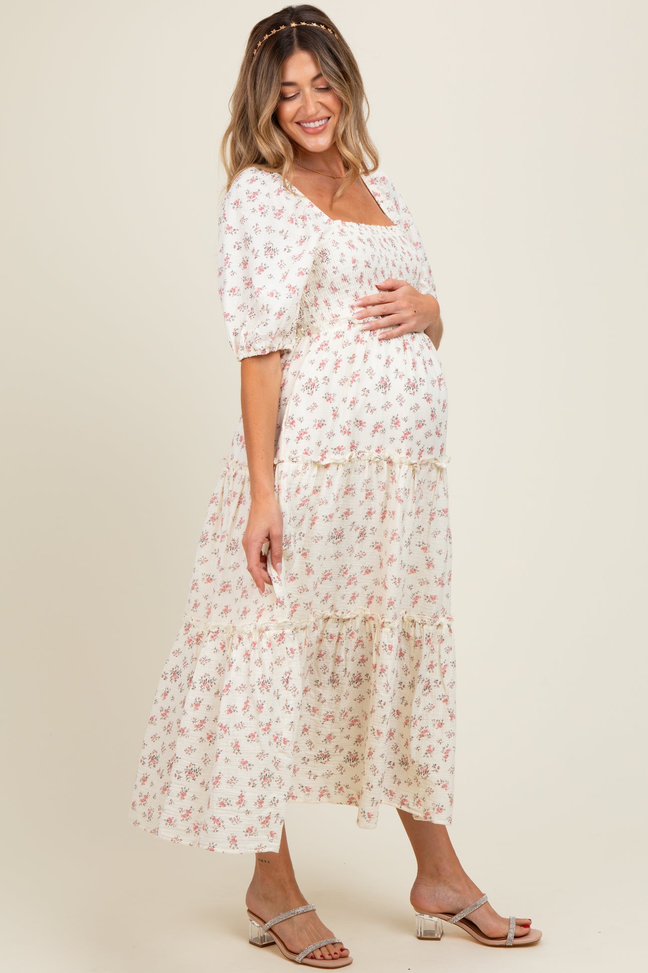 woman wearing a floral print maternity maxi dress with puff sleeves and holding her baby bump