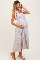 woman wearing a light gray floral maternity dress with tie straps, highlighting her baby bump