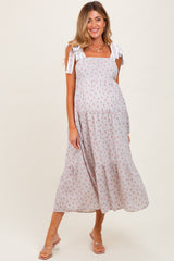 woman wearing a floral print maternity maxi dress with tie straps and a baby bump visible