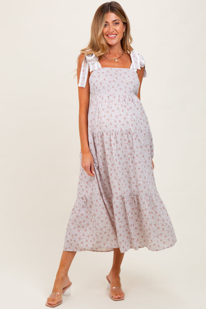woman wearing a floral print maternity maxi dress with tie straps and a baby bump visible