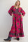 woman wearing a bright pink floral maxi dress with pockets and long sleeves, styled with ankle boots