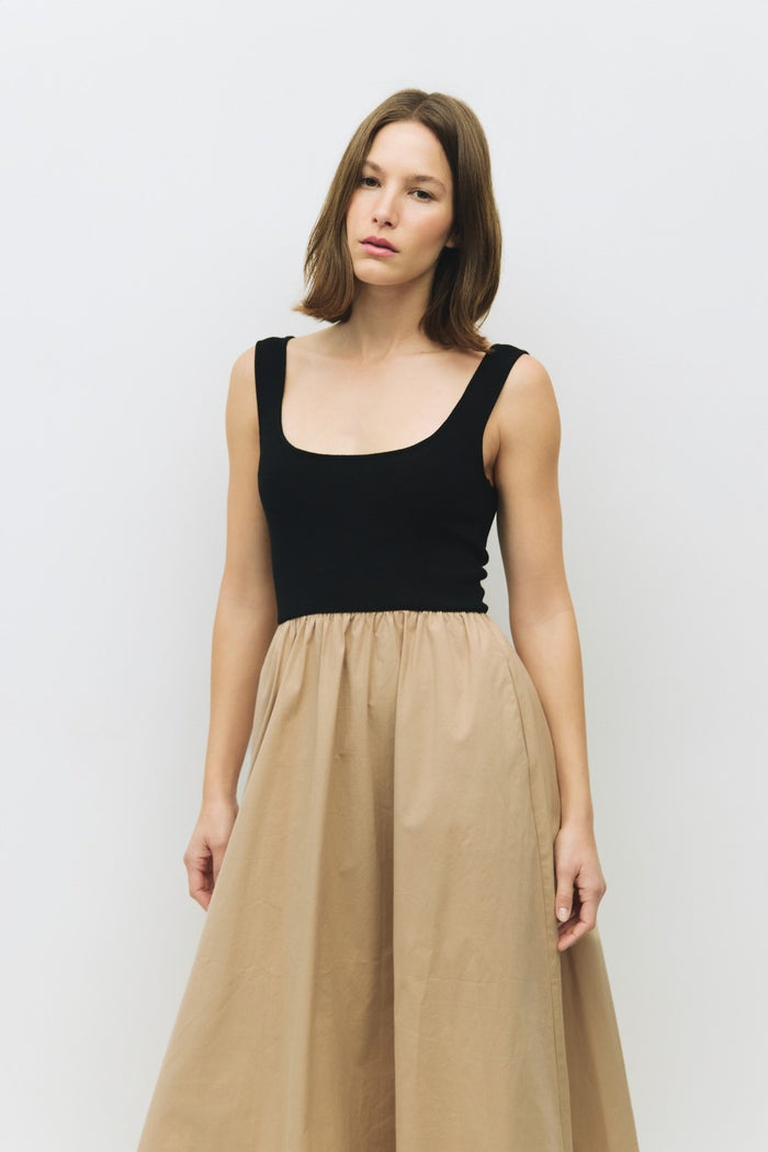 woman wearing a black sleeveless top with a scoop neckline and a beige flowy skirt
