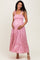 woman wearing a light pink maternity maxi dress with smocked bodice and tiered skirt, holding her baby bump