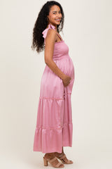 woman wearing a pink maternity maxi dress with smocked bodice and adjustable straps, showing her baby bump