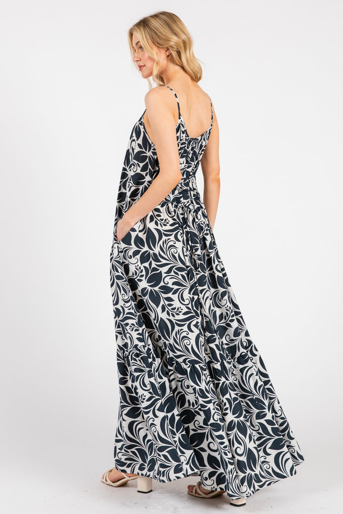 woman wearing a navy blue and white floral maxi dress with adjustable straps and side pockets