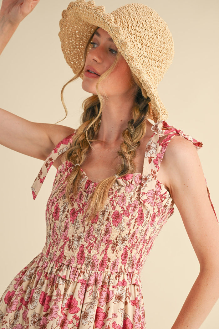 woman wearing a floral smocked sundress with tie straps and a straw sun hat