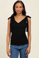 woman wearing a black ribbed tank top with bow tie shoulder accents and blue jeans