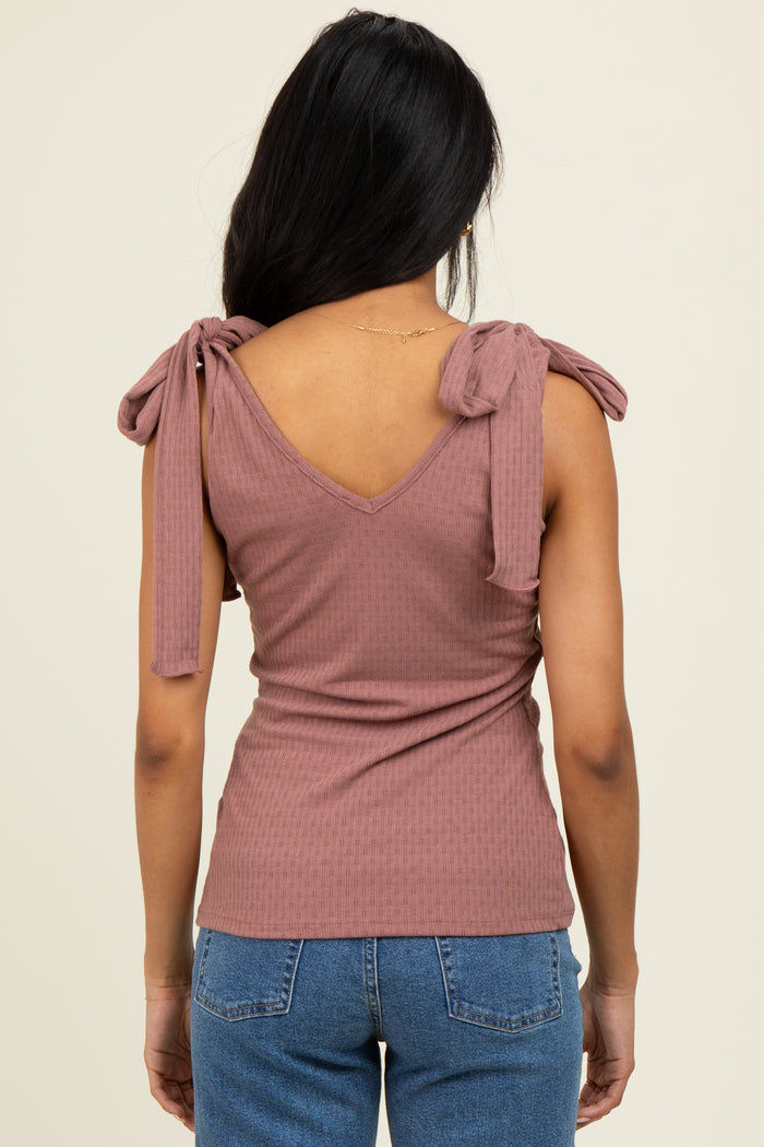woman wearing a mauve ribbed top with v-neck and tie shoulder details, seen from the back