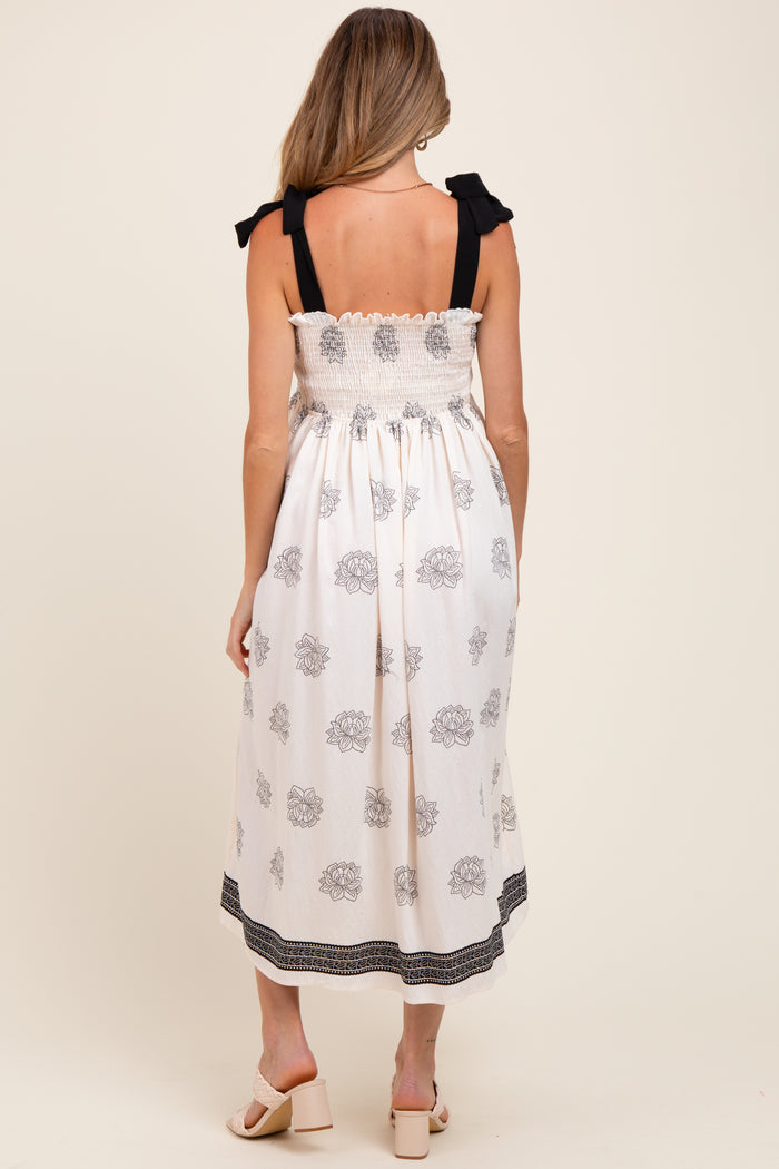 woman wearing a white maternity dress with floral print and black ruffle straps, showing a maternity-friendly design