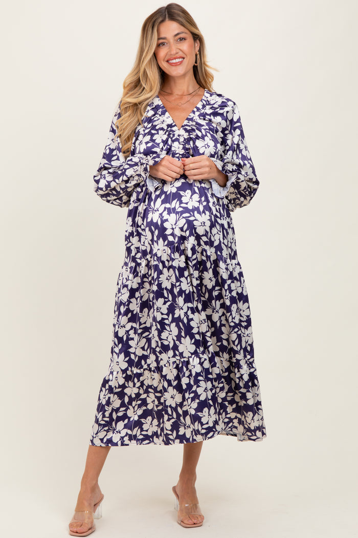 woman wearing a navy floral maternity dress with a v-neckline and long sleeves, showing her baby bump
