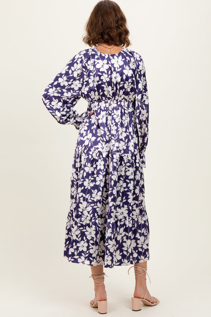 woman wearing a purple floral maxi dress with long sleeves and cinched waist, shown from the back