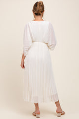 woman wearing a white pleated maternity dress with a relaxed fit, showcasing a flowing silhouette and half sleeves