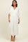 woman wearing a white pleated maxi dress with a deep v-neck and balloon sleeves