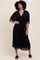 woman wearing a black pleated maxi dress with a deep v-neck and flutter sleeves