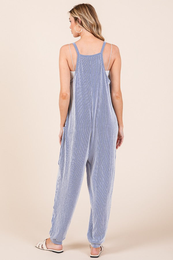 woman wearing a navy and white striped sleeveless jumpsuit with adjustable straps and a relaxed fit