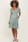 woman wearing a green floral maternity dress with ruffled sleeves and a tiered skirt
