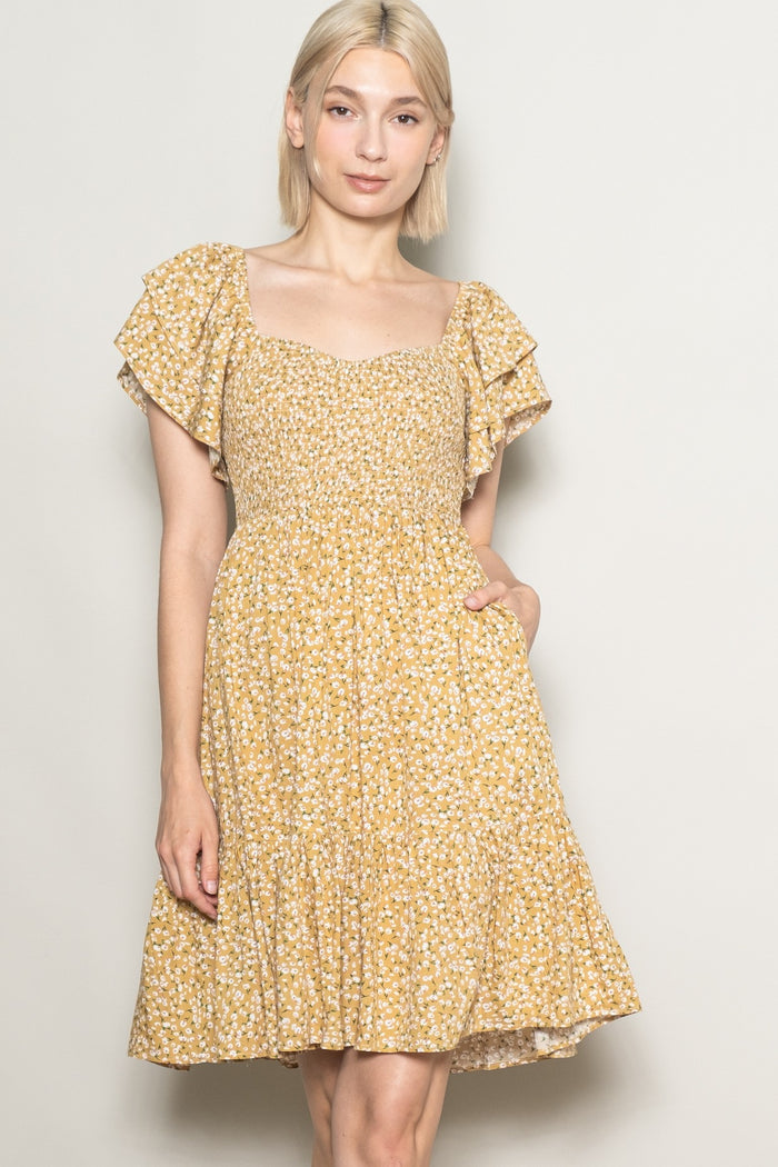 woman wearing a mustard yellow floral print dress with ruffle sleeves and a square neckline