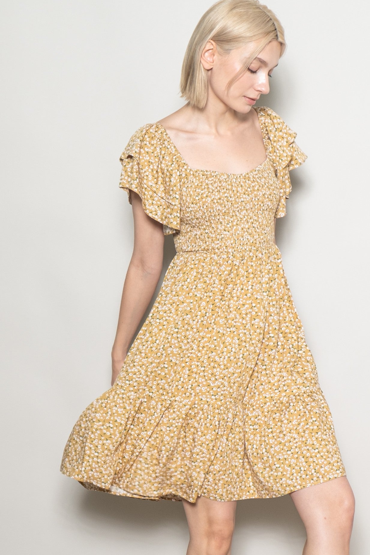 woman wearing a yellow floral print dress with ruffled sleeves and a fitted bodice