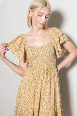 woman wearing a yellow floral smocked dress with flutter sleeves and a square neckline