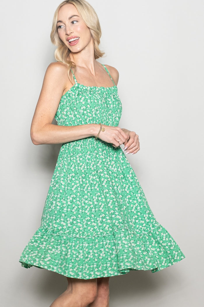woman wearing a green floral sundress with a tiered skirt and spaghetti straps