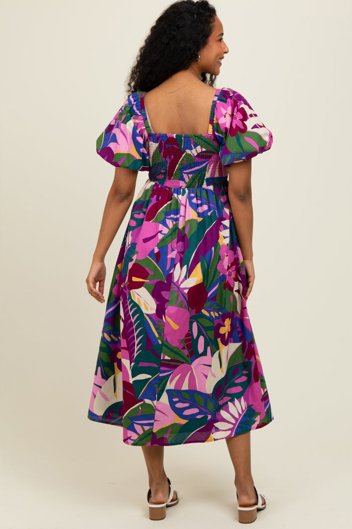 woman wearing a colorful floral print midi dress with puff sleeves and a smocked bodice, showing the back view