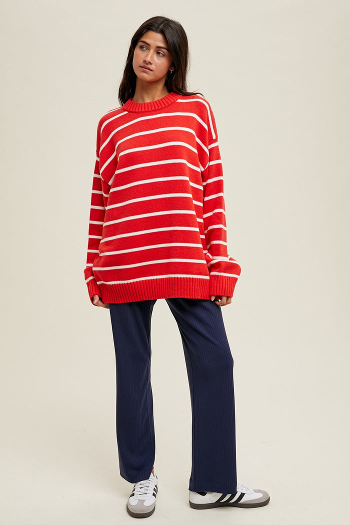 woman wearing a red and white striped oversized sweater and navy wide-leg pants with white sneakers