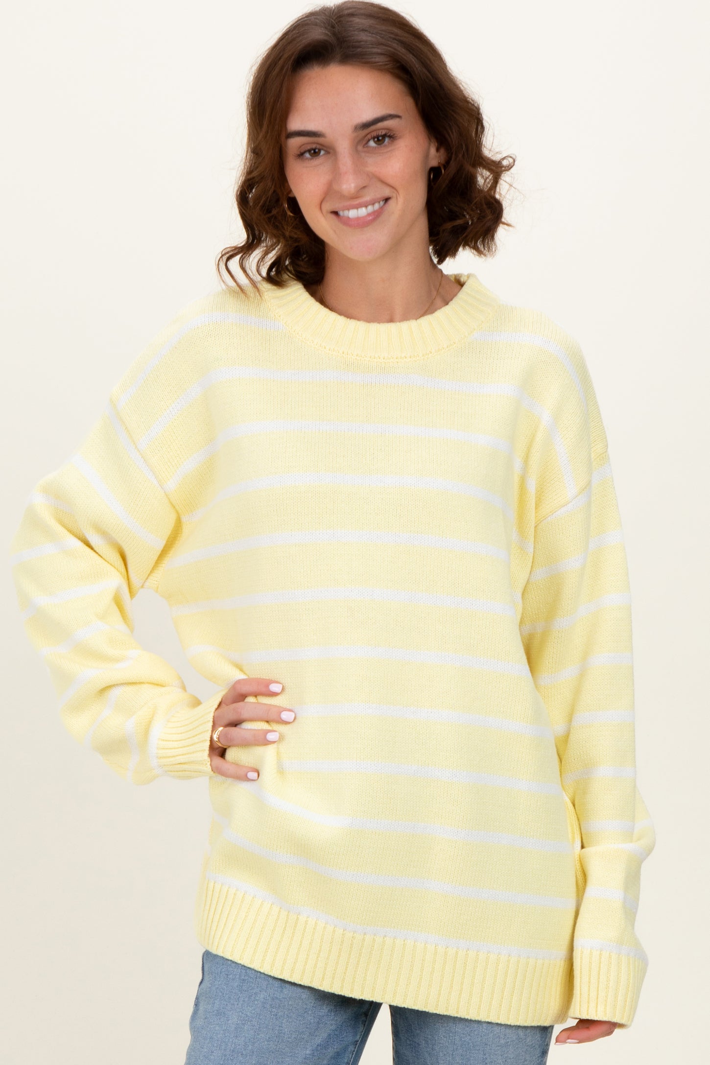 woman wearing a yellow and white striped oversized sweater with a ribbed neckline and long sleeves