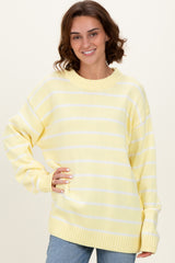 woman wearing a yellow and white striped oversized sweater with a ribbed neckline and long sleeves