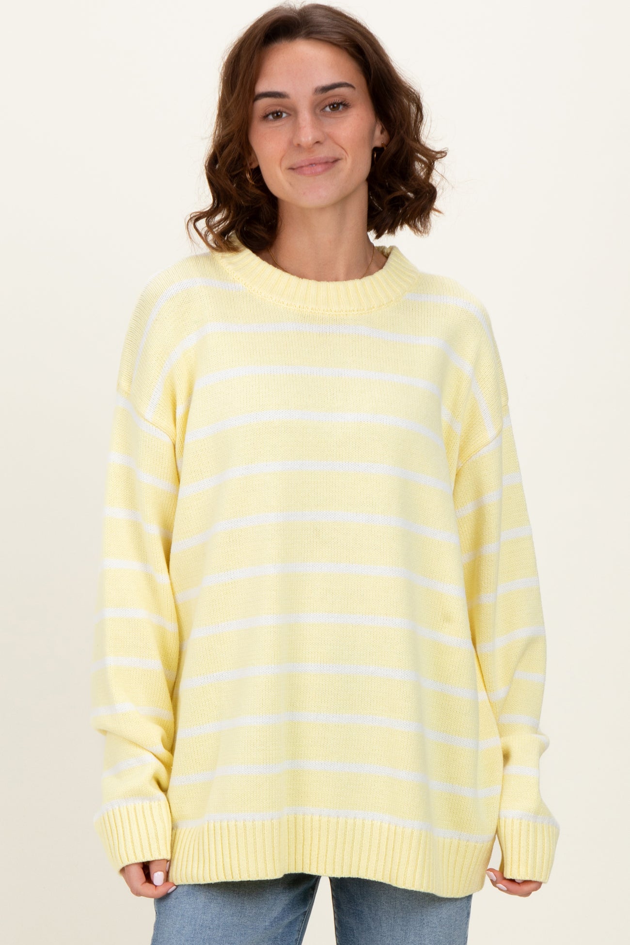 woman wearing a yellow striped oversized sweater with a relaxed fit and ribbed cuffs