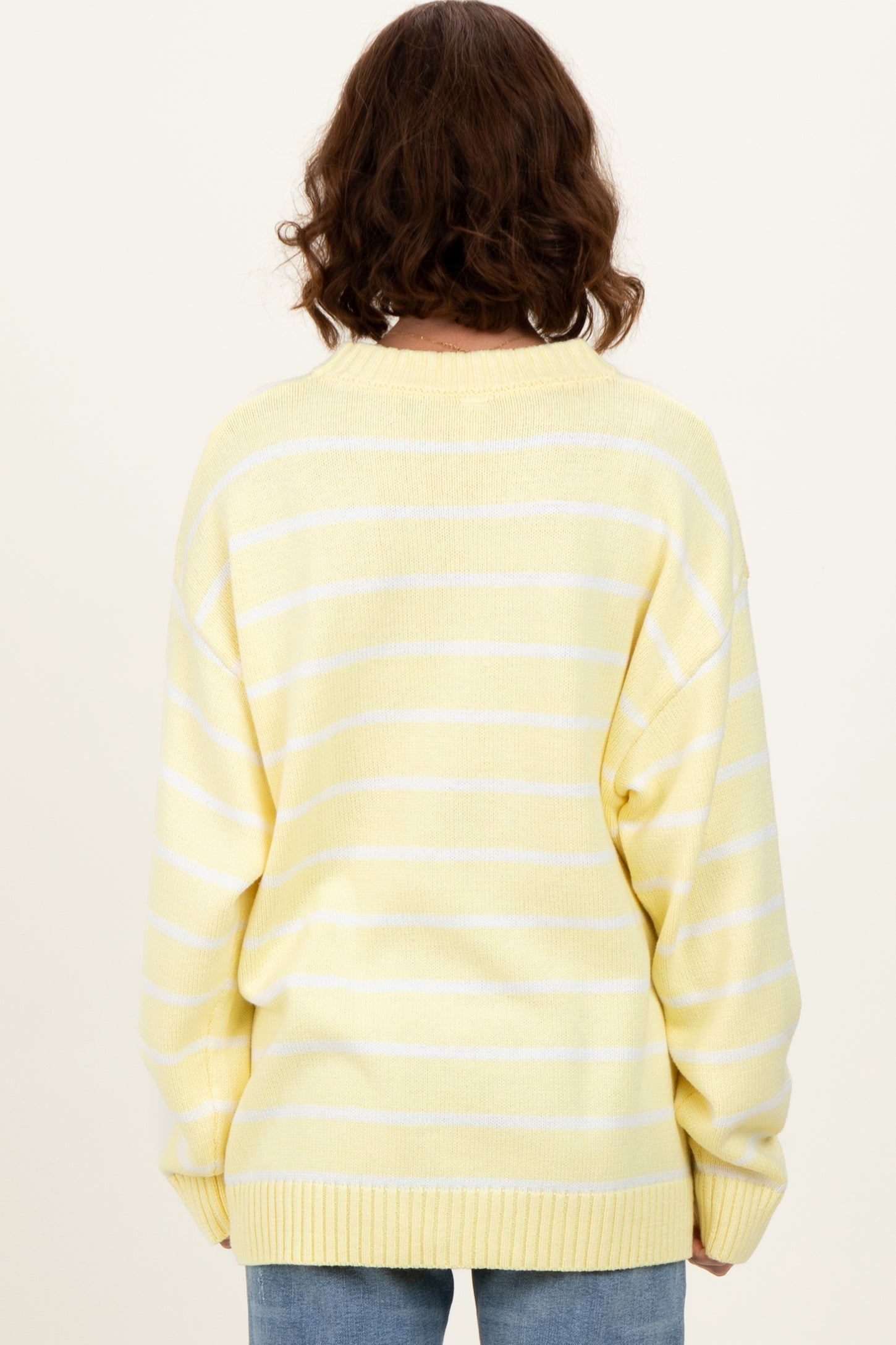 woman wearing a yellow and white striped oversized sweater, viewed from the back