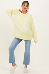 woman wearing a yellow striped oversized maternity sweater and blue flared jeans