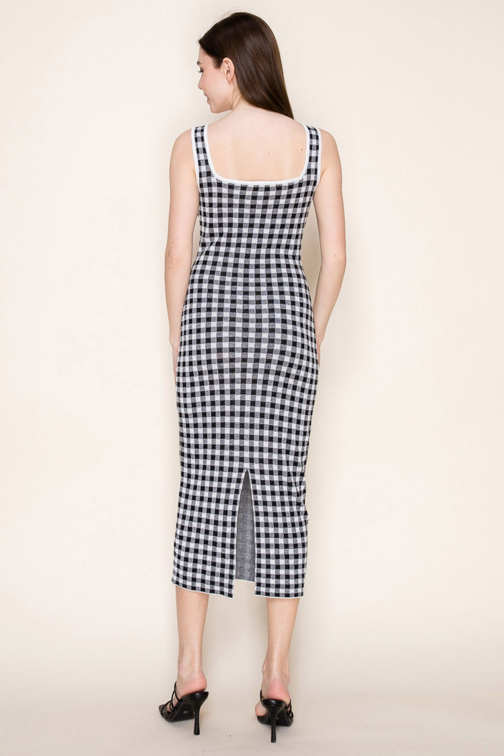 woman wearing a black and white gingham midi dress with a fitted silhouette and a back slit