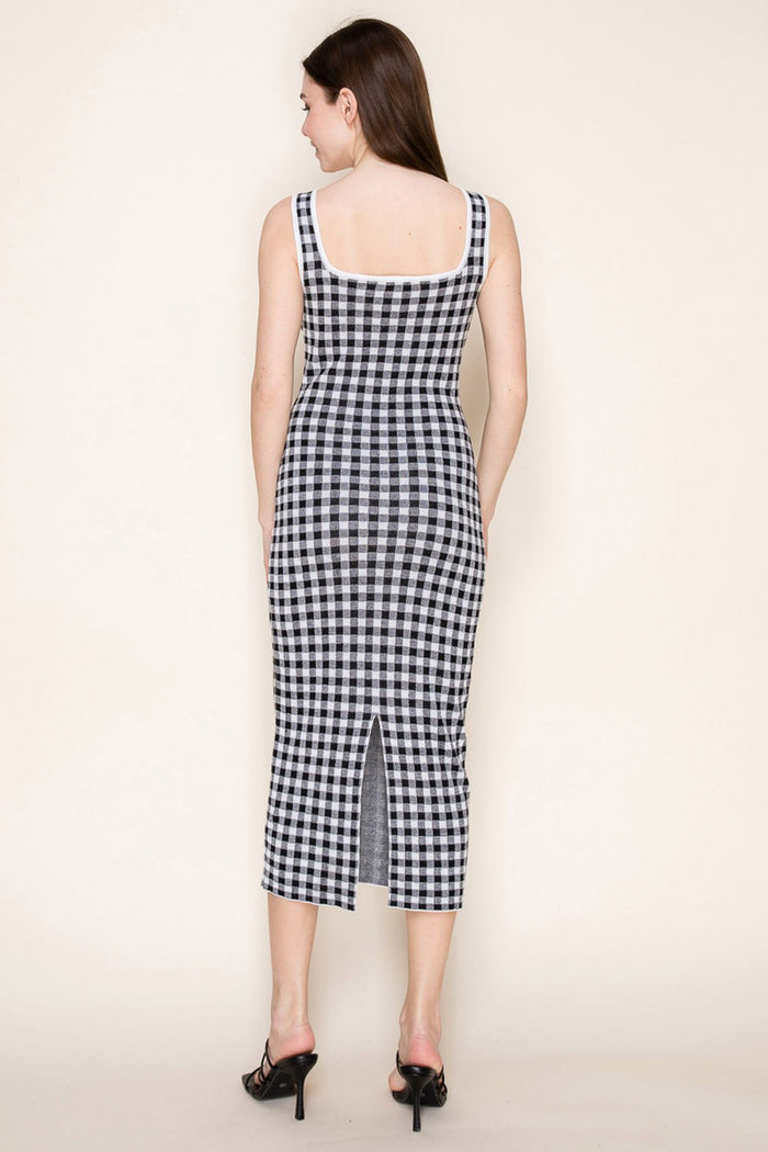 woman wearing a black and white gingham midi dress with a fitted silhouette and a back slit