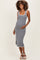 woman wearing a black and white gingham maternity dress, showing her baby bump, standing in a relaxed pose