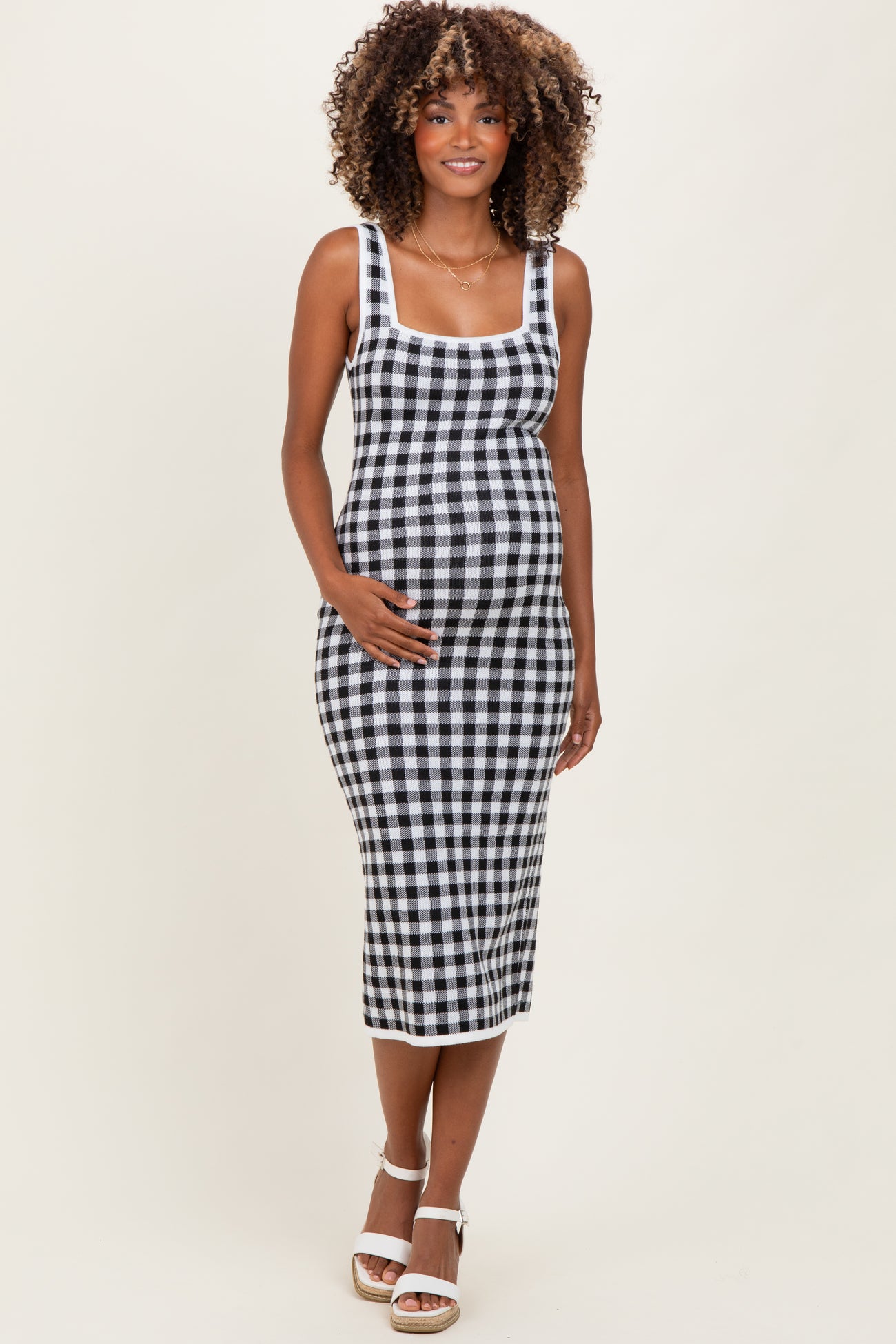 woman wearing a black and white checkered maternity dress with a fitted silhouette and her baby bump visible