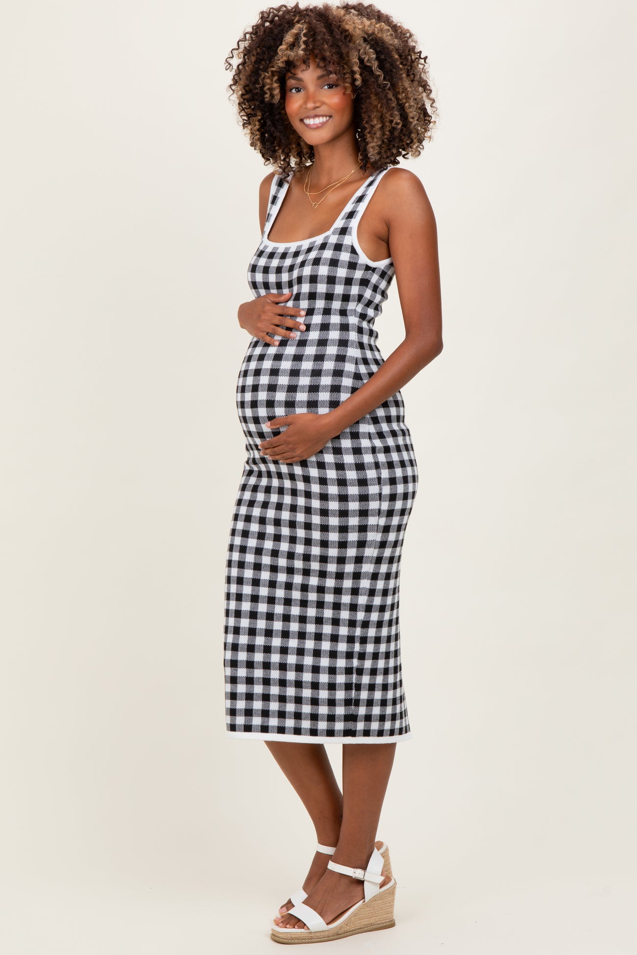 woman wearing a black and white checkered maternity dress and holding her baby bump