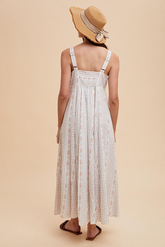 woman wearing a long white floral maxi dress with adjustable straps and a straw hat, seen from the back