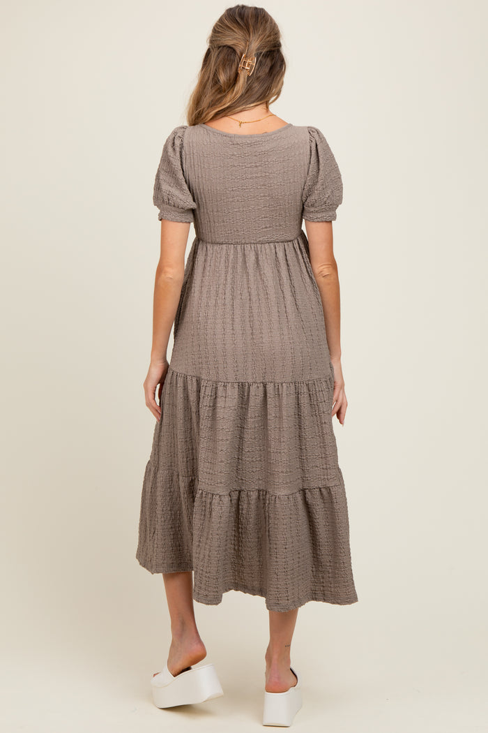 woman wearing a taupe tiered maternity dress with short puff sleeves and a comfortable fit