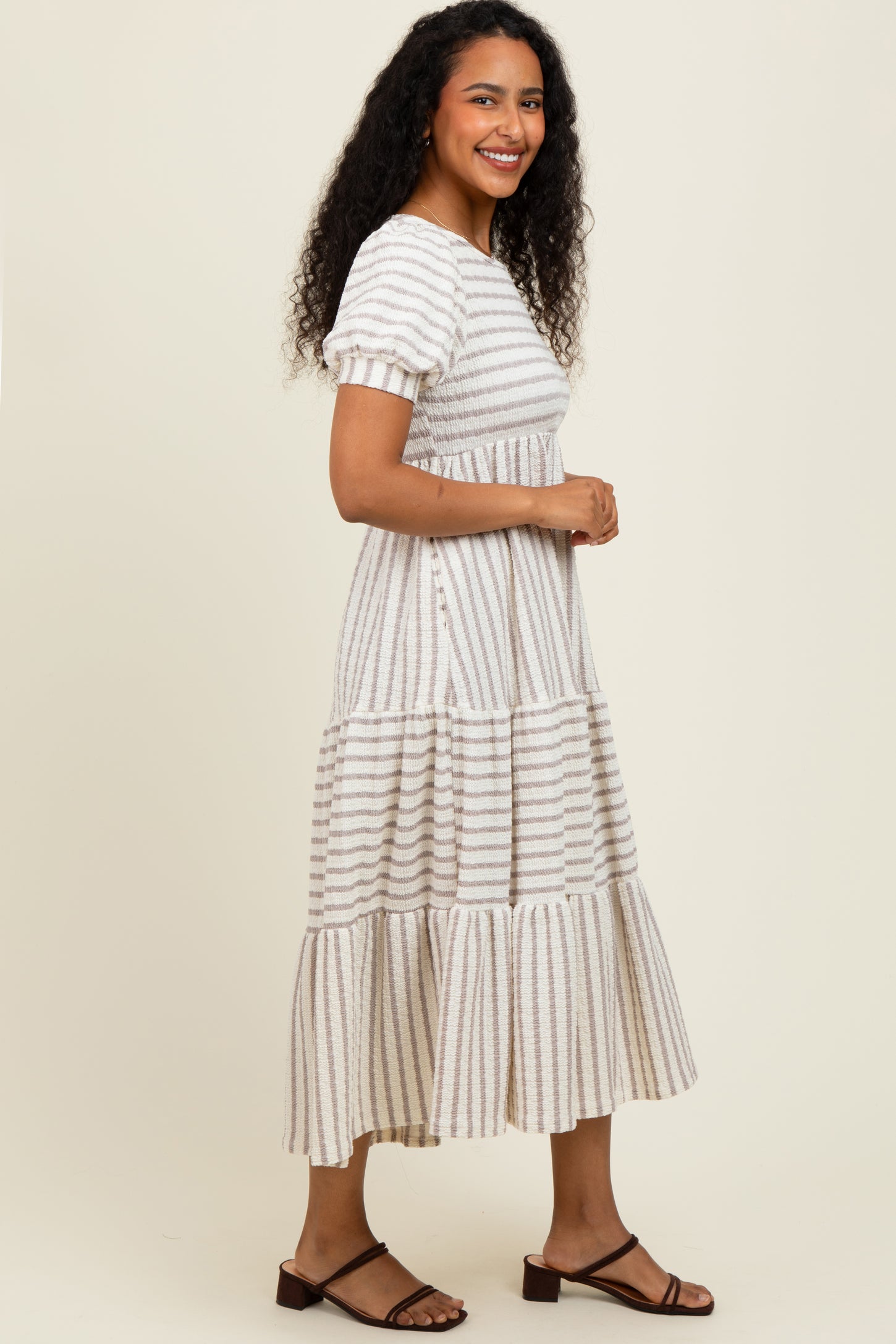 woman wearing a beige striped tiered maxi dress with short sleeves and a relaxed fit