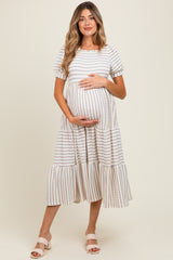 woman wearing a cream and beige striped maternity dress with a tiered design, holding her baby bump