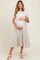 woman wearing a cream and beige striped maternity dress with a tiered design, holding her baby bump