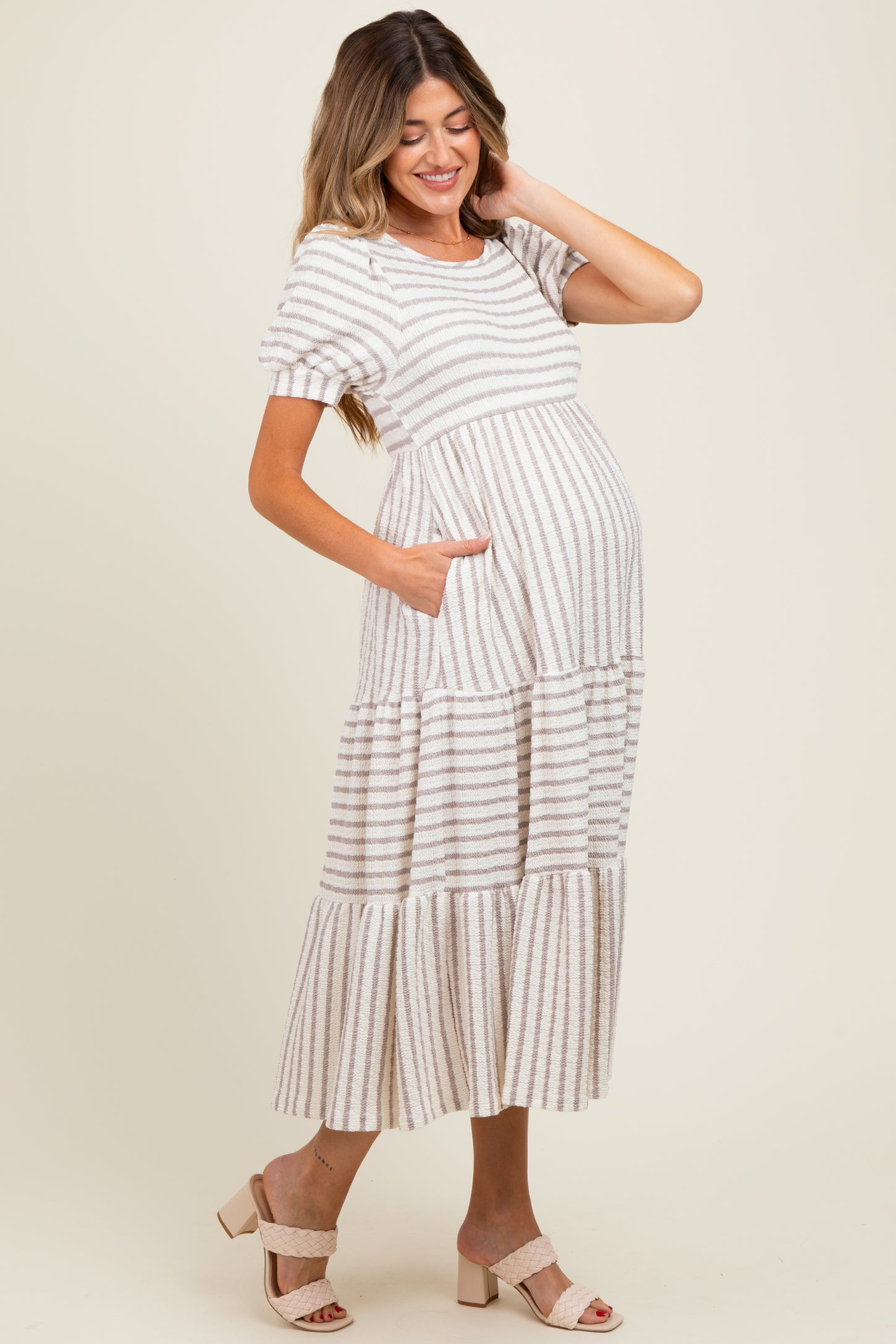 woman wearing a striped maternity maxi dress with short sleeves and pockets, showing off her baby bump